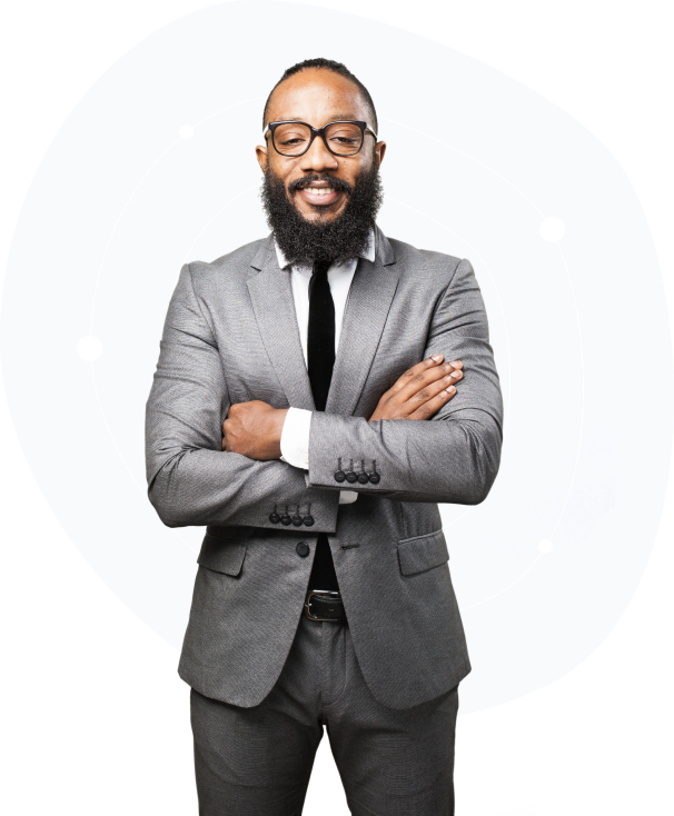 slider1.png Young man with a beard and glasses wearing a grey suit, white shirt, and black tie, standing confidently with arms folded in front of a white and grey Canva background